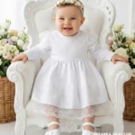 Elegancka biała sukienka do chrztu dla dziewczynki z długim rękawem i koronkowym dołem.