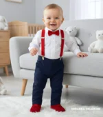 Elegancki komplet niemowlęcy na chrzest: biała koszula, granatowe spodnie, czerwone szelki i mucha.