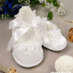 Balerinki do chrztu dla dziewczynki ecru zdobione koronką i atłasową wstążką.