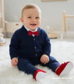 Eleganckie ubranko do chrztu dla chłopca: granatowy sweterek, biała koszula i czerwona mucha.