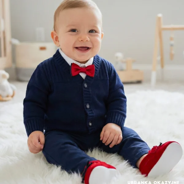 Eleganckie ubranko do chrztu dla chłopca: granatowy sweterek, biała koszula i czerwona mucha.