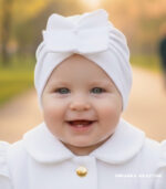 Biały turban dla dziewczynki do chrztu z dużą ozdobną kokardą, elegancka czapeczka niemowlęca.