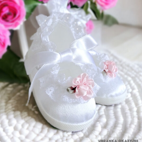 Białe balerinki do chrztu dla niemowlaka ozdobione delikatną koronką i różową różyczką