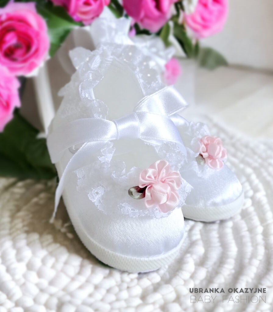 Białe balerinki do chrztu dla niemowlaka ozdobione delikatną koronką i różową różyczką