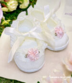 Satynowe balerinki do chrztu dla dziewczynki w kolorze ecru, zdobione koronką i różowym kwiatkiem, wiązane wstążką