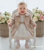 Elegancki beżowy płaszczyk dla dziewczynki do chrztu ozdobiony złotymi kokardkami.
