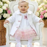 Biały płaszczyk do chrztu dla dziewczynki zapinany na ozdobne różowe kokardki, idealny na wiosnę i jesień.