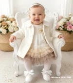 Elegancki płaszczyk do chrztu dla dziewczynki w kolorze ecru, zapinany na guziki z ozdobnymi kokardkami.