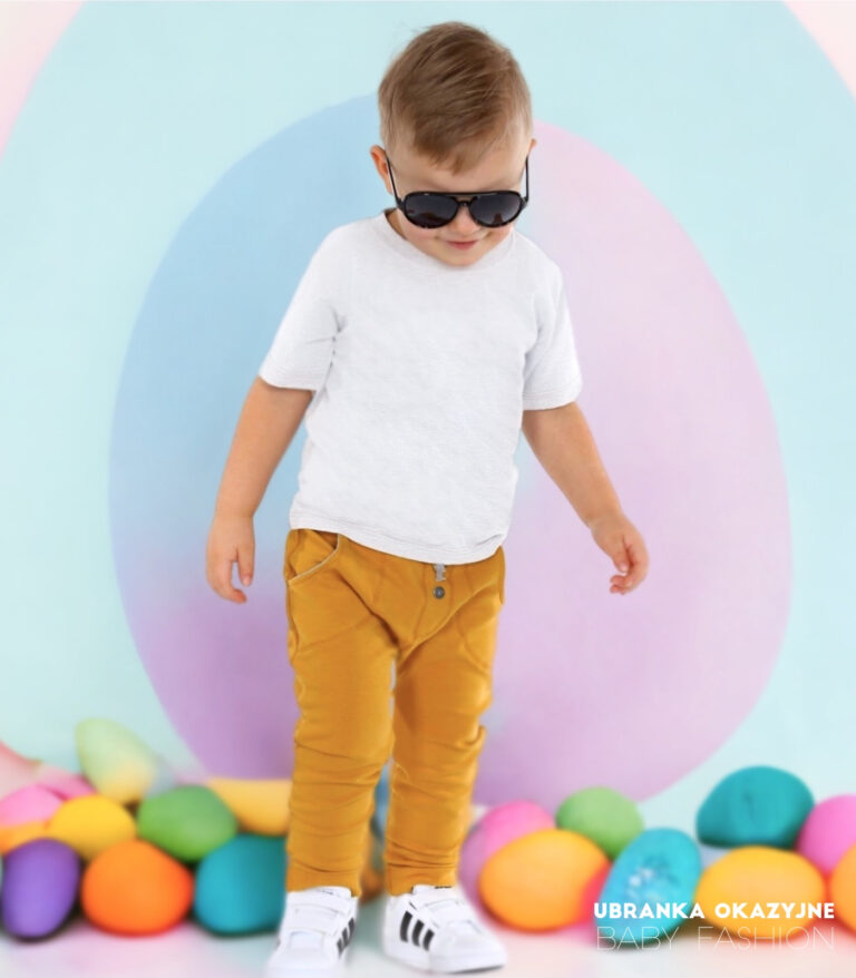 Musztardowe spodnie dla chłopca w eleganckiej stylizacji z białą koszulką i trampkami.