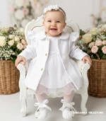 Biały płaszczyk do chrztu dla dziewczynki z ozdobnymi falbankami i złotymi guzikami.