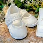 Satynowe balerinki niemowlęce w kolorze ecru ozdobione perełkami na pasku, idealne buciki do chrztu.