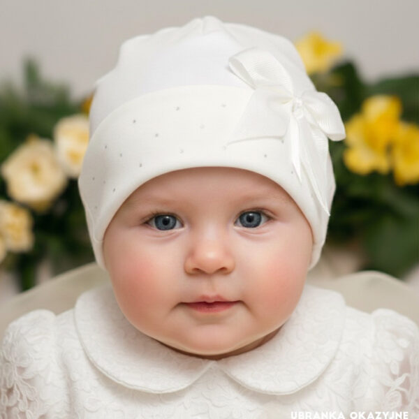 Elegancka czapeczka niemowlęca w kolorze ecru, idealna na Chrzest Święty, ozdobiona kokardą.