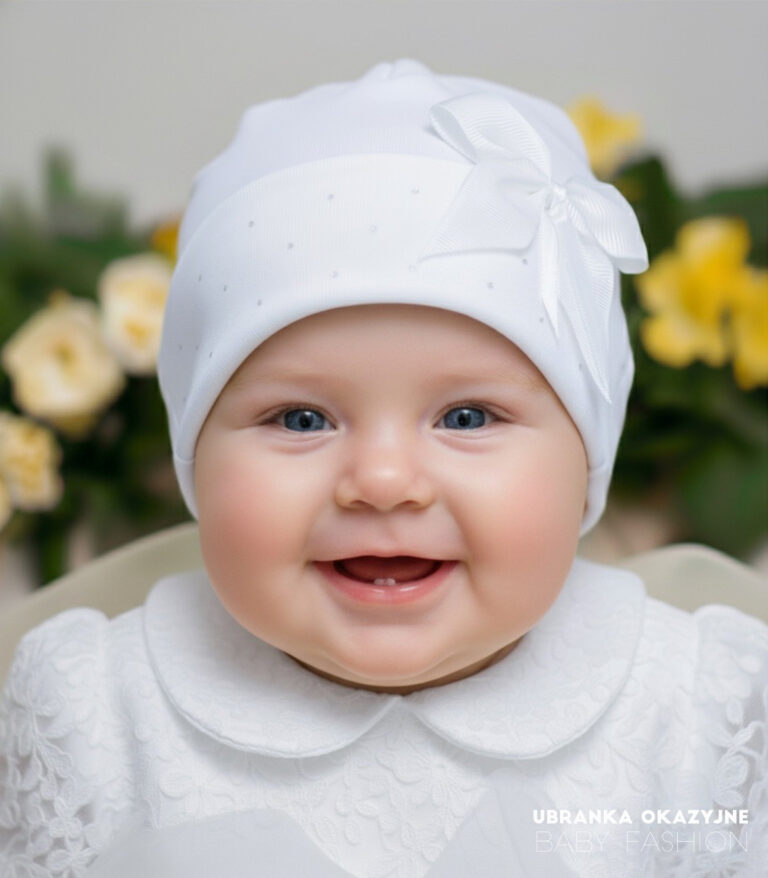 Biała czapka dla dziewczynki do chrztu z ozdobną kokardą i delikatnymi cekinami.