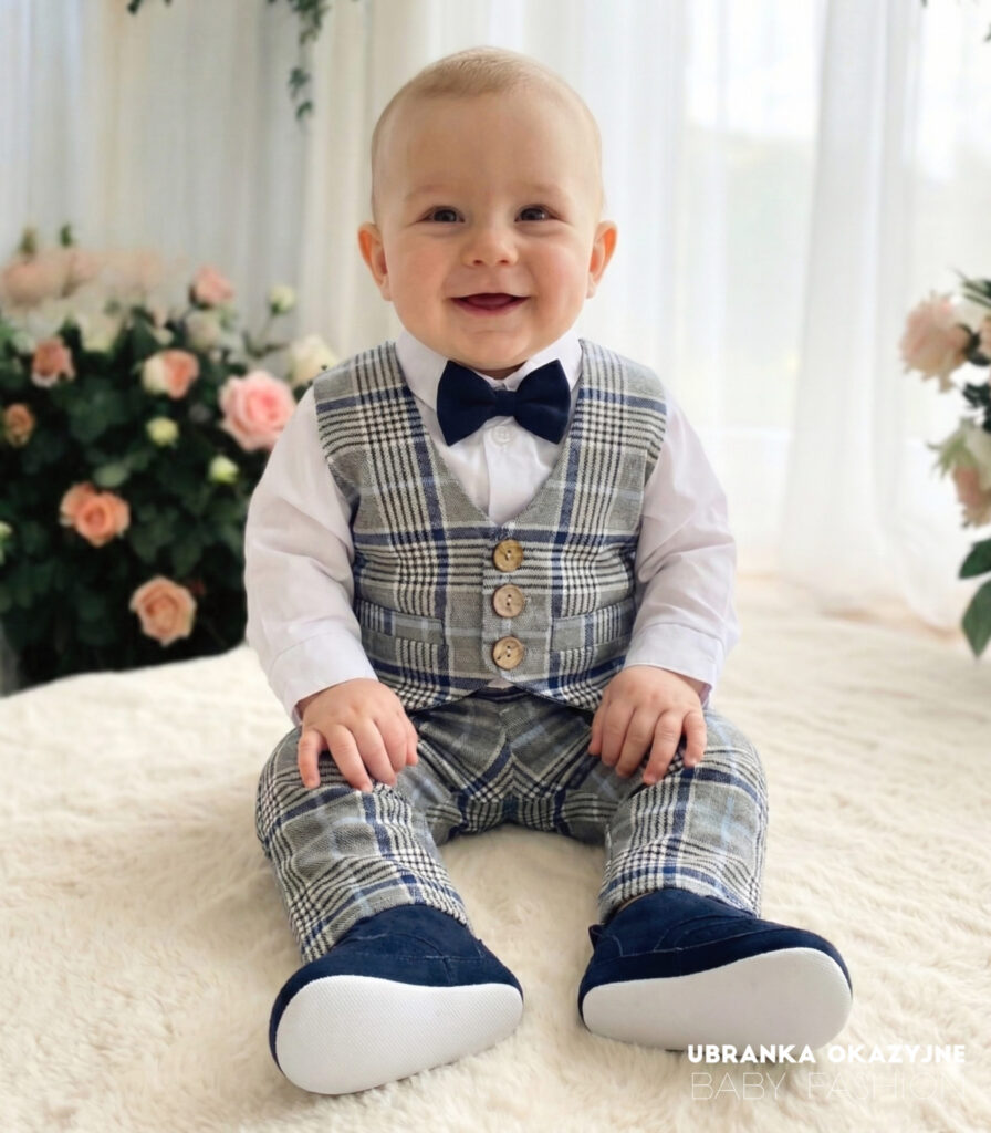 Eleganckie ubranko do chrztu dla chłopca: szara kamizelka i spodnie w niebieską kratę, biała koszula oraz granatowa muszka.