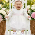 Elegancka sukienka na chrzest dla dziewczynki z długim rękawem i rozkloszowanym tiulowym dołem.