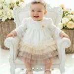 Elegancka sukienka do chrztu z długim rękawem i tiulowym dołem w odcieniach beżu i brązu.