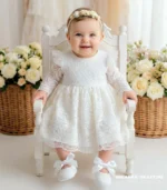 Elegancka koronkowa sukienka do chrztu w kolorze ecru z długim rękawem i tiulowymi detalami na ramionach.