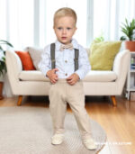 Elegancki komplet do chrztu dla chłopca: beżowe spodnie, białe koszulobody, szelki w kratkę i mucha