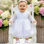 Biała koronkowa sukienka do chrztu dla dziewczynki z długim rękawem.